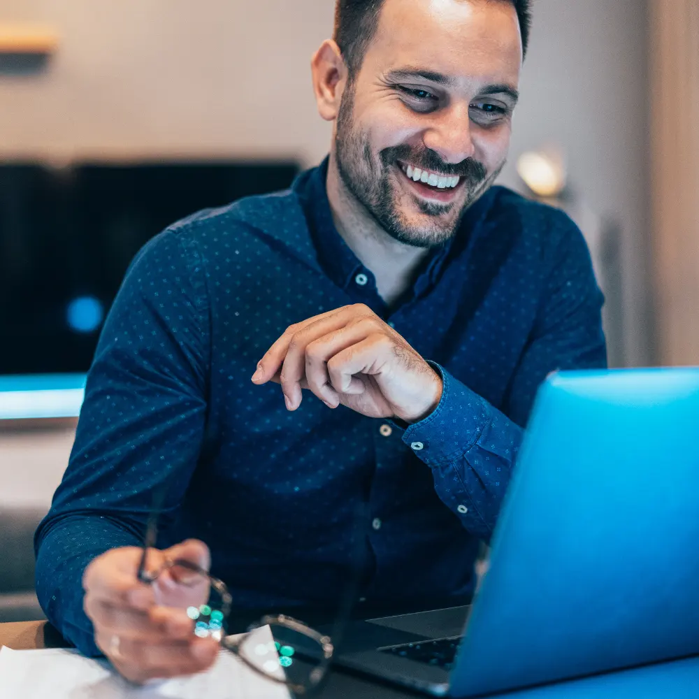 A business leader smiling at his computer.