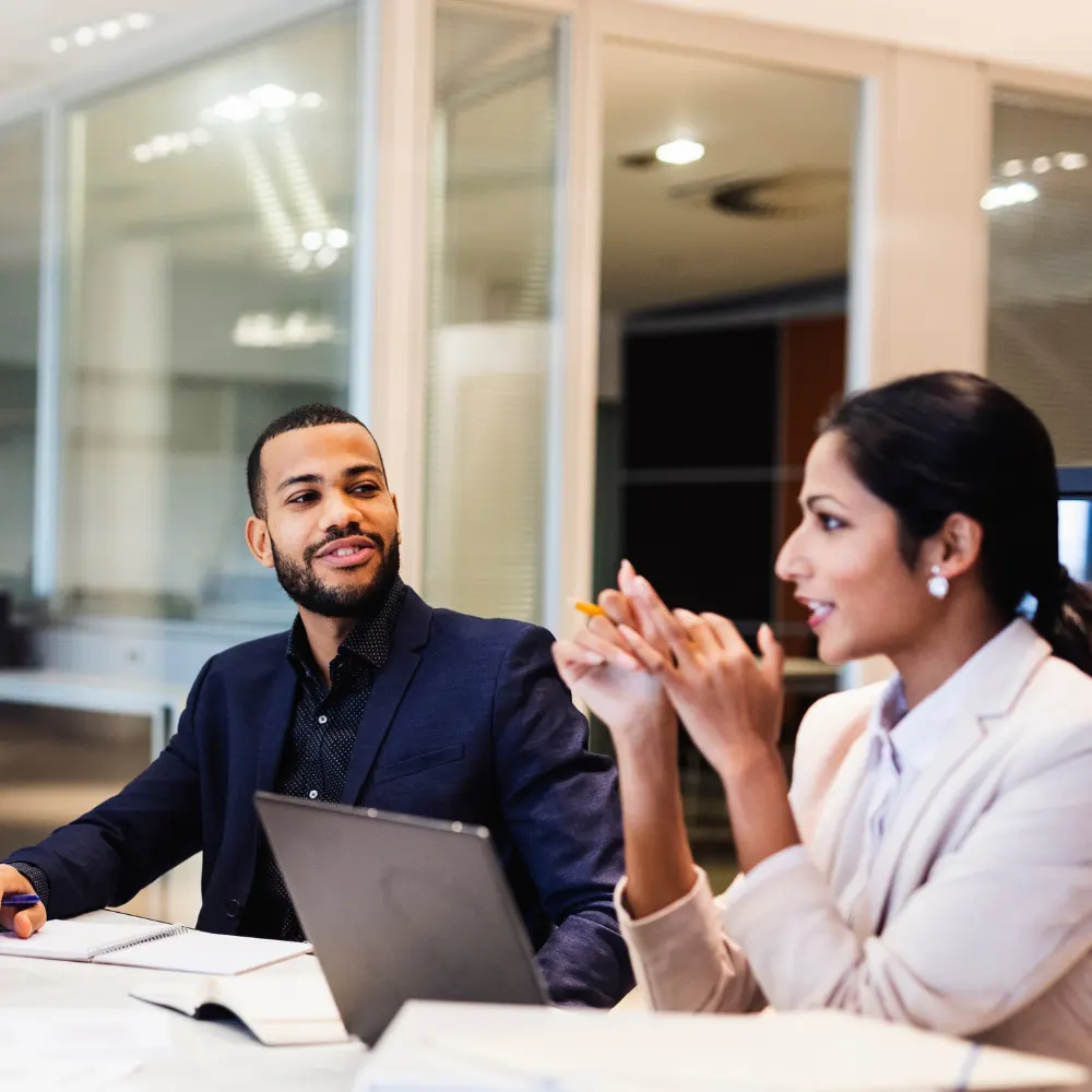 A lively team meeting showing two people deep in conversation.