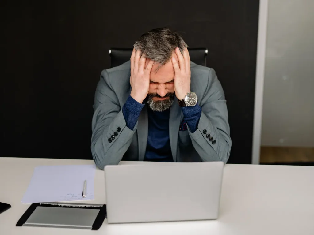 Business leader frustrated and fed-up with his head in his hands.