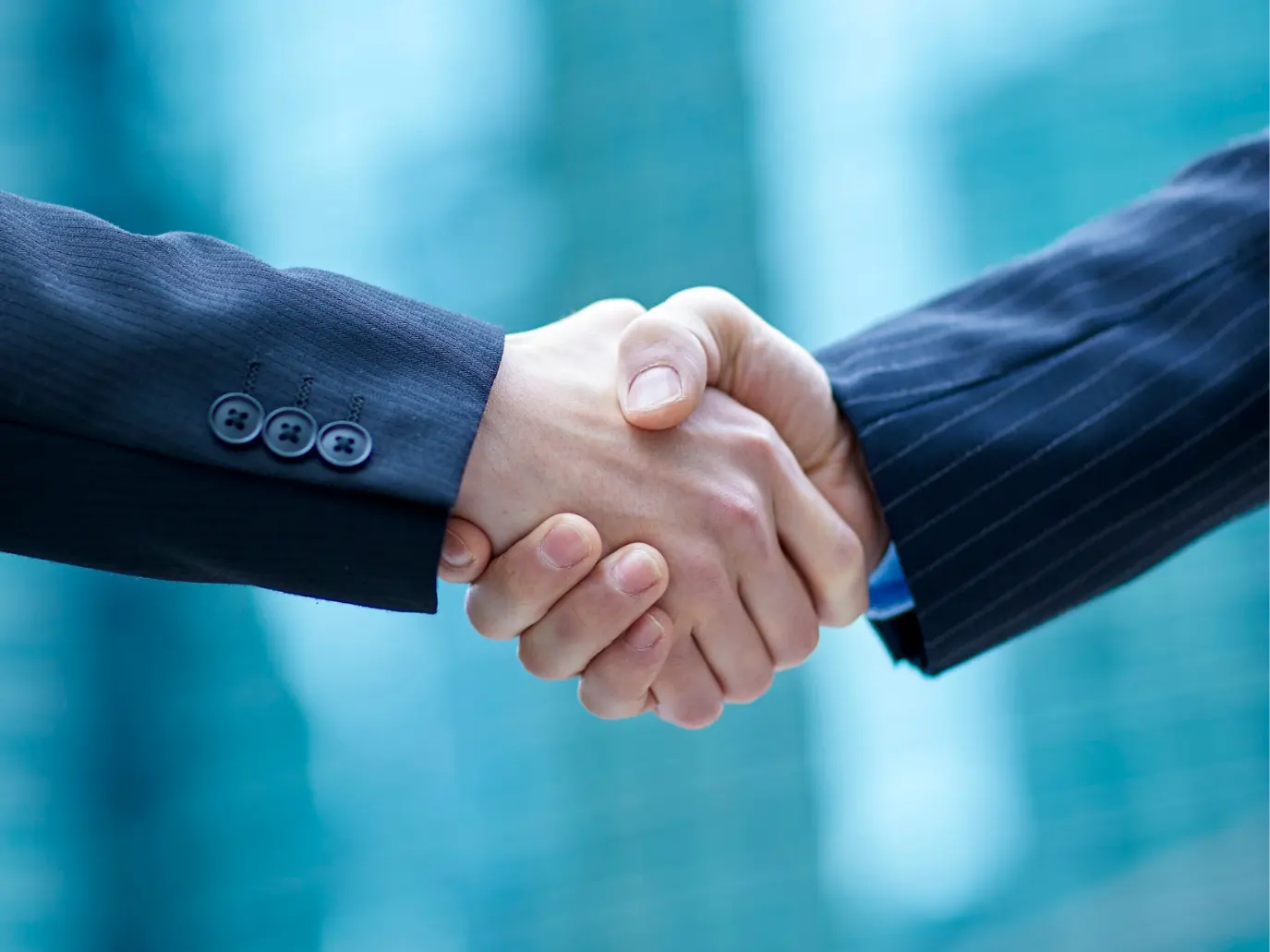 Two business leaders shaking hands at the end of a deal.